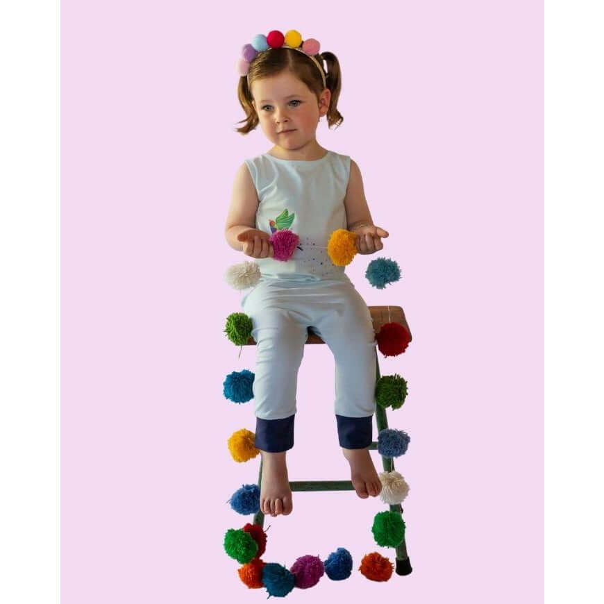 little girl toddler sitting on chair with colourful decorations in her hand modelling a leon and bird romperoo romper